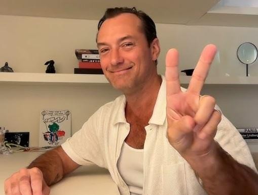 Jude Law w otoczeniu dzieci, uśmiechnięty, w ciepłej, rodzinnej atmosferze.