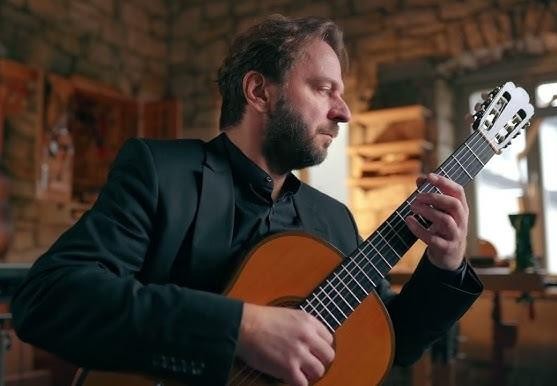 Zbliżenie na dłonie Marcina Dylli podczas gry na gitarze klasycznej, ukazujące precyzję i pasję wykonania.