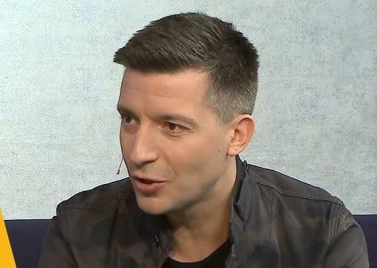 Michał Cessanis podczas prelekcji, z entuzjazmem opowiadający o podróżach, w tle ekran z widokiem na australijski krajobraz.