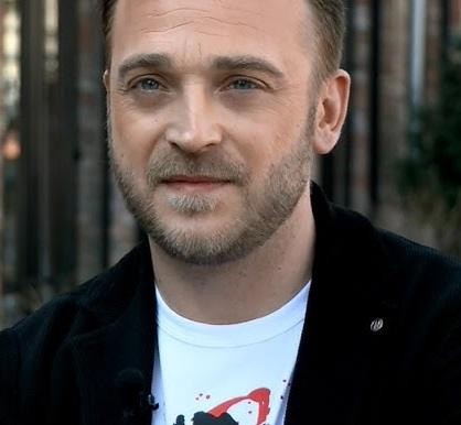 Mateusz Gessler, szef kuchni, skupiony na przygotowywaniu potrawy w profesjonalnej kuchni.
