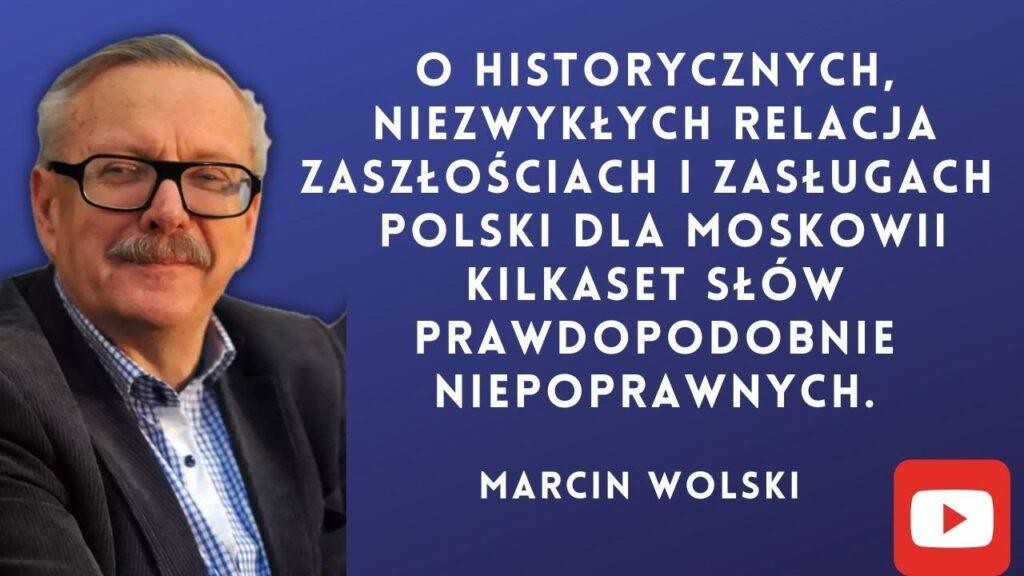 Marcin Wolski w studiu radiowym podczas nagrywania audycji, uśmiechnięty, w otoczeniu sprzętu nagraniowego.