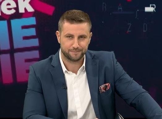 Miłosz Kłeczek podczas dynamicznej dyskusji w studiu telewizyjnym, gestykulujący.