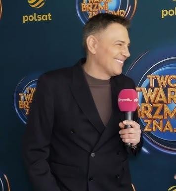 Krzysztof Ibisz w otoczeniu rodziny, uśmiechnięty w domowym otoczeniu, symbolizujący jego życie prywatne i rodzinne.