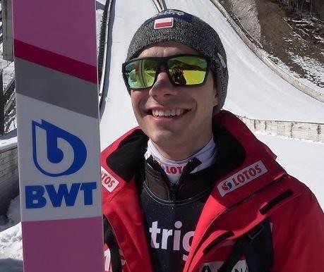 Jakub Wolny na treningu na skoczni narciarskiej, skupiony na przygotowaniu do skoku.